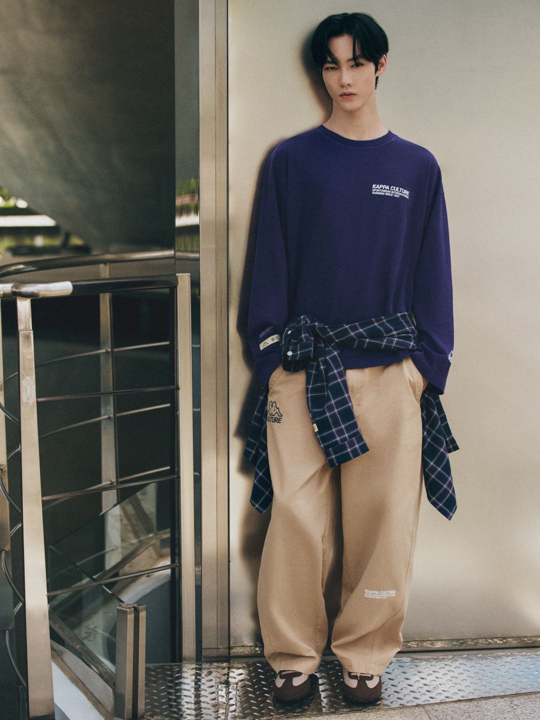 Model in purple sweatshirt and beige wide-leg trousers from the collaboration