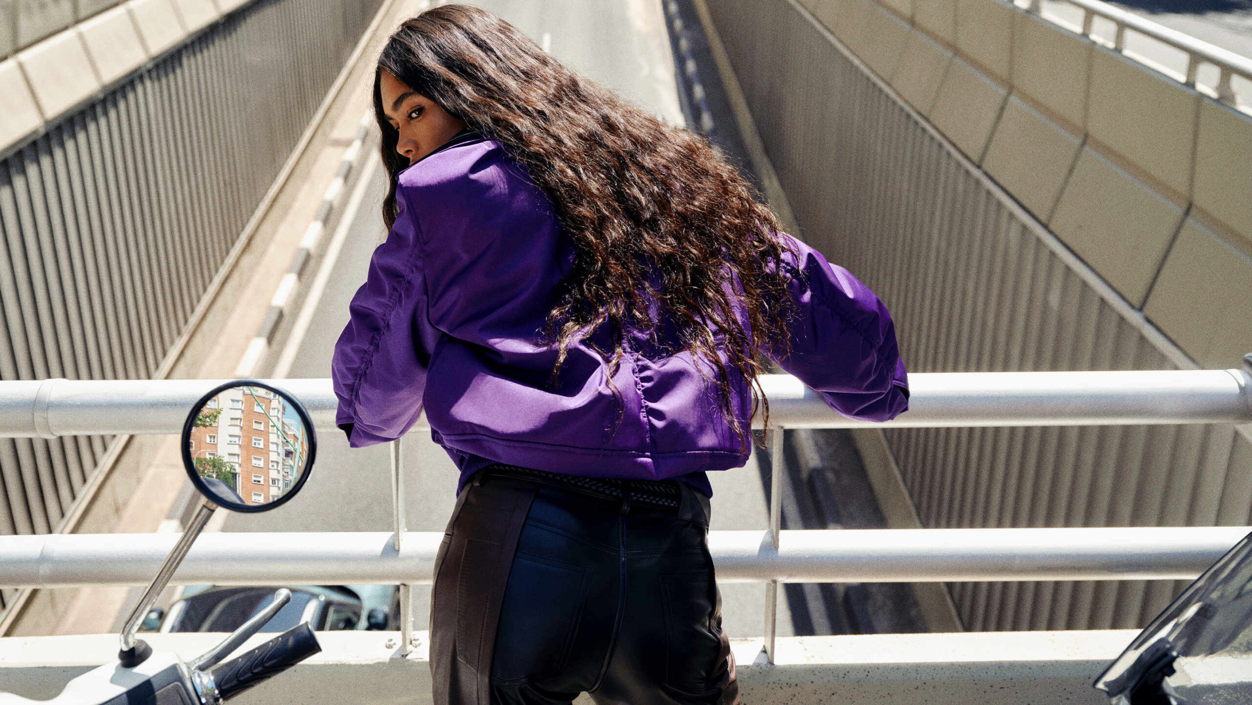 Model in purple knitwear on a Madrid escalator in the Loewe precollection campaign