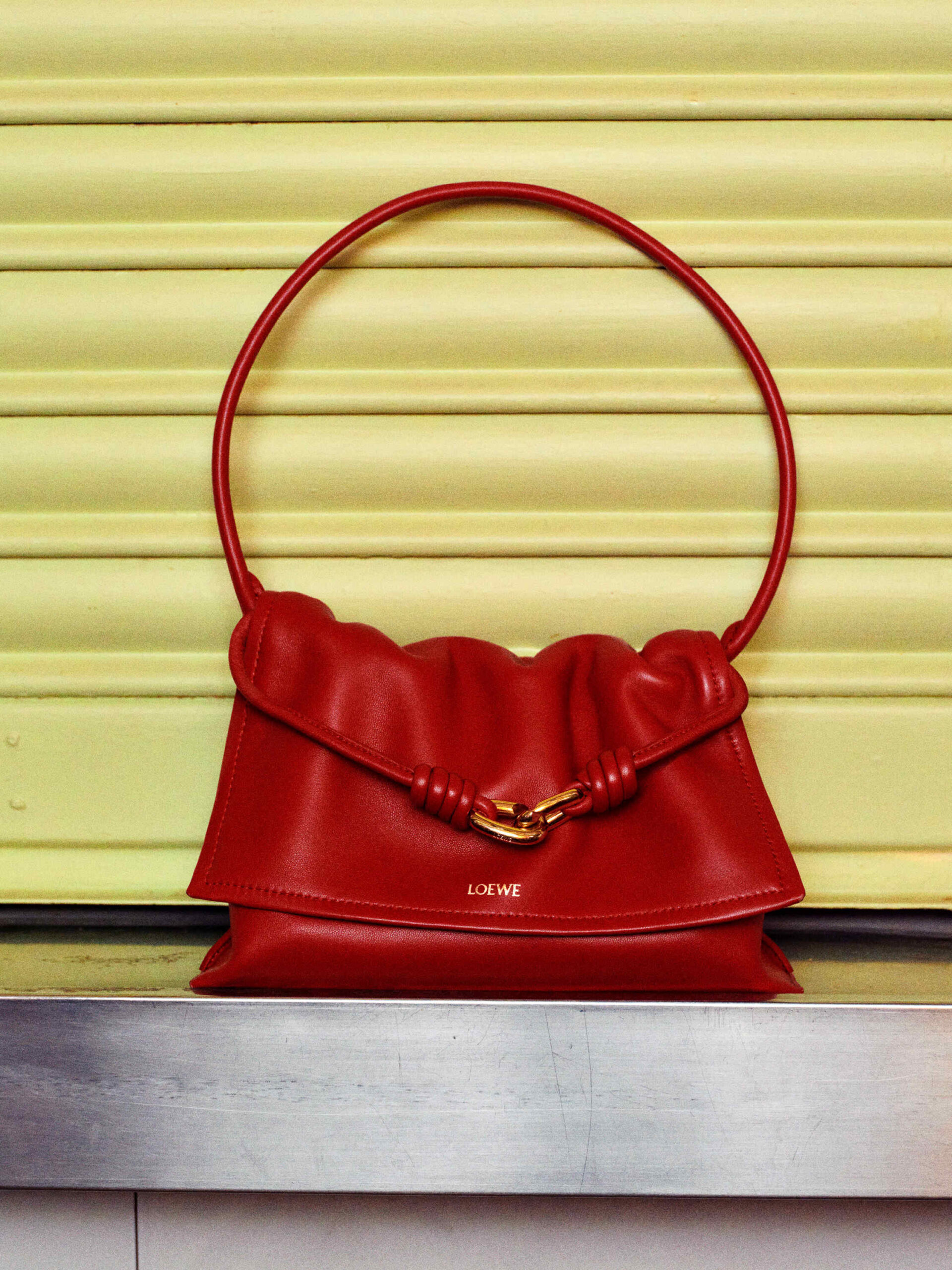 Red Loewe handbag against a yellow shutter