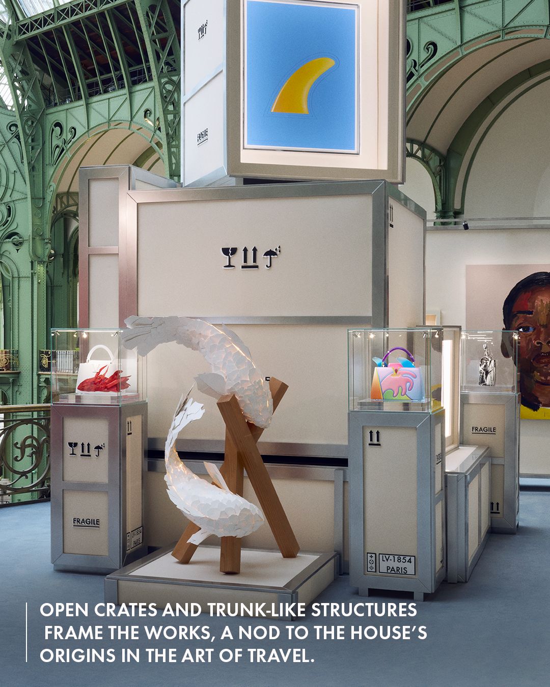 A fish sculpture, artworks and Artycapucines bags displayed among stacked crates at the Grand Palais, with the source’s travel-concept text overlay.
