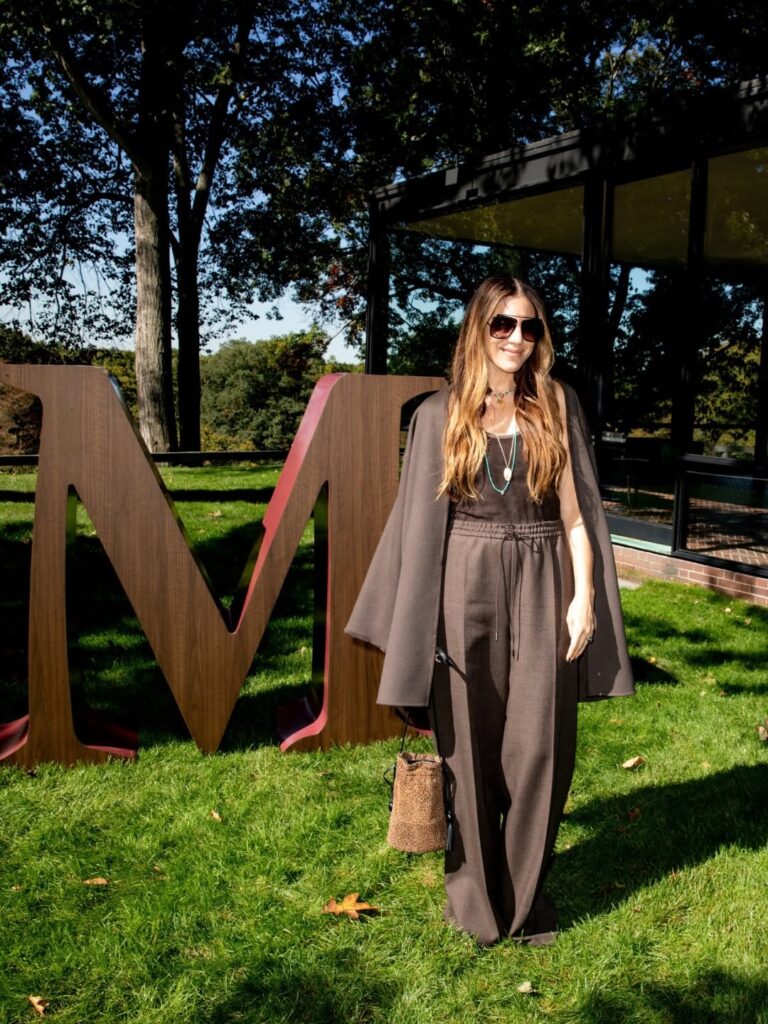 Guest in a brown coat beside a Max Mara installation at The Glass House