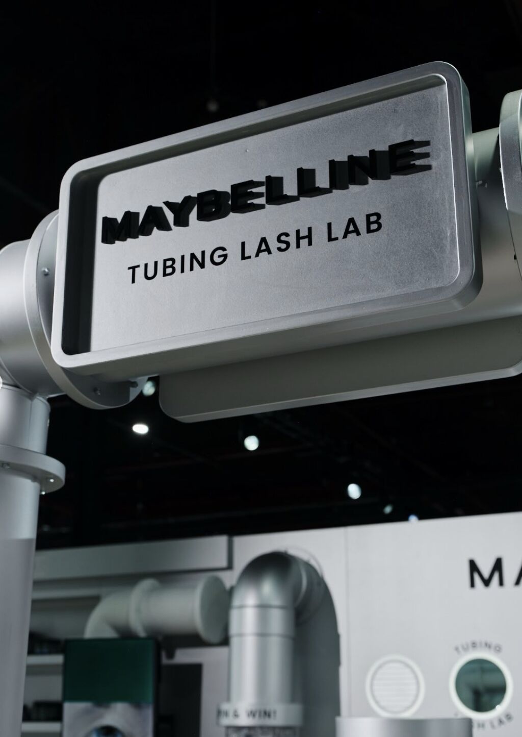 Maybelline Tubing Lash Lab sign mounted on silver pipework