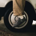 Grey Mercedes-Benz and adidas Samba worn beside a car wheel