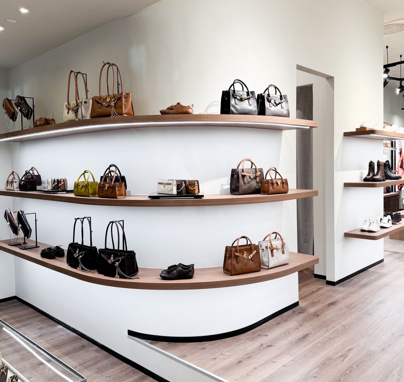 Handbags and shoes on curved shelving in the Michael Kors boutique