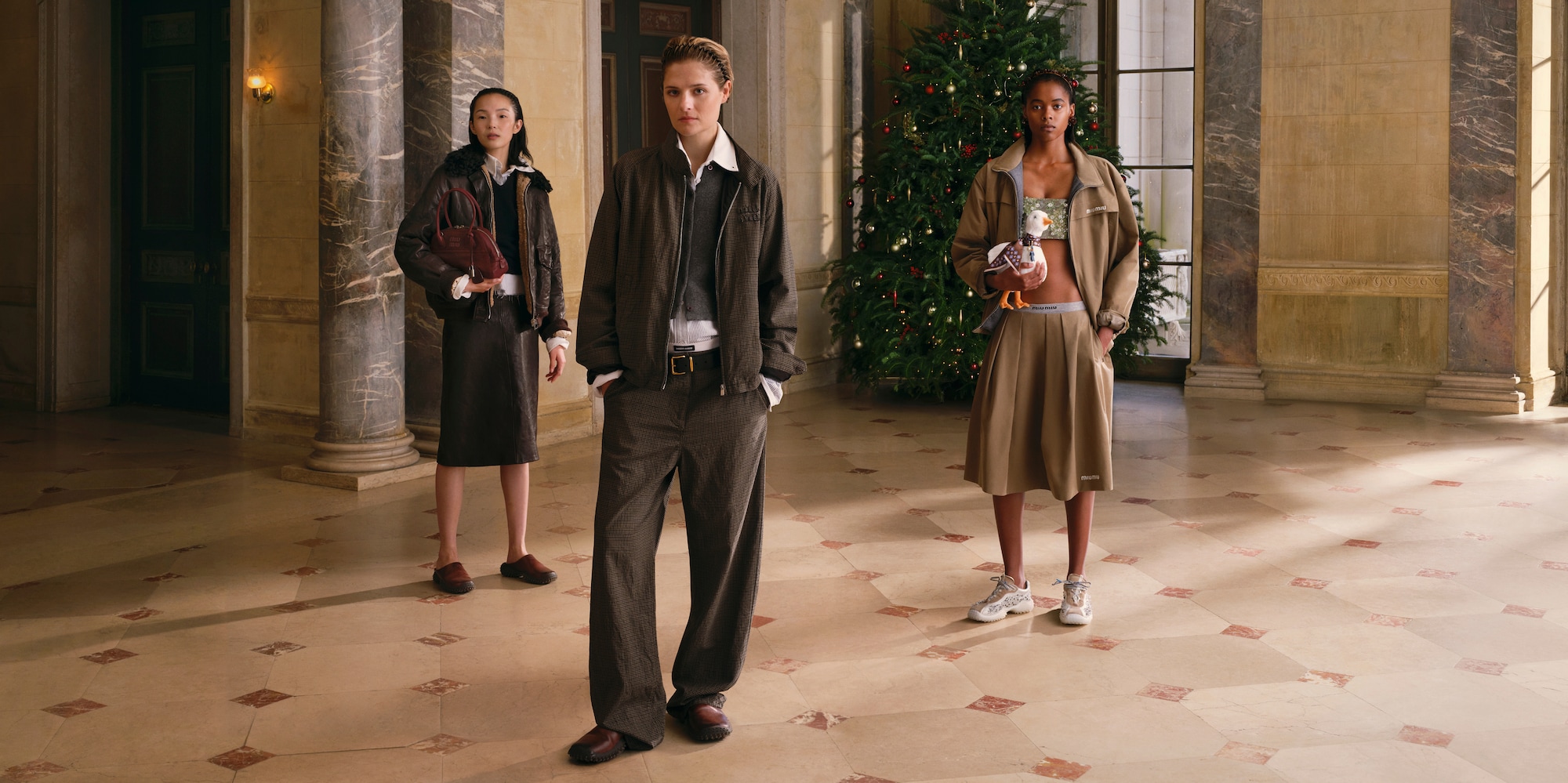 Three models in a townhouse entrance in the Miu Miu Holiday 2026 campaign