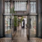 Entrance to Moncler’s Fifth Avenue flagship in New York, with glass doors, dark stone framing and a checkerboard floor.