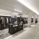 Moncler retail space with dark display units and illuminated signage at Le Bon Marché