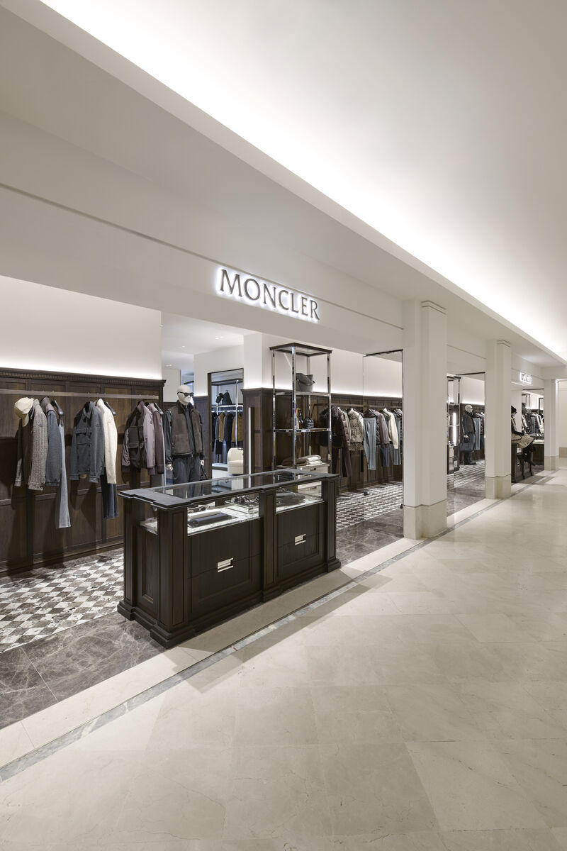 Moncler retail space with dark display units and illuminated signage at Le Bon Marché