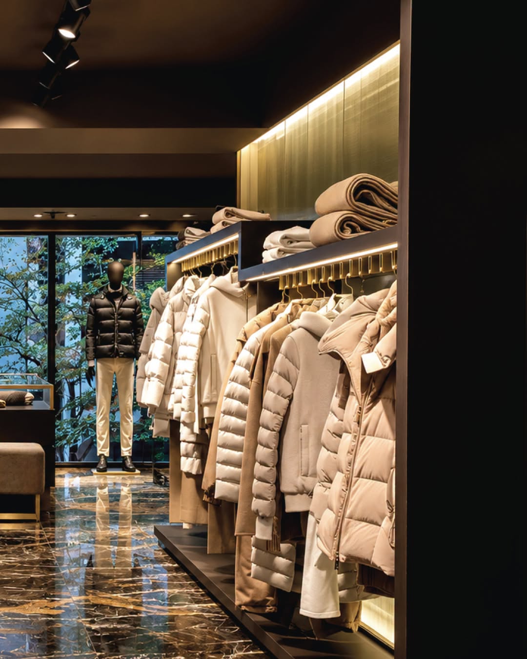 Neutral outerwear displayed along illuminated rails at MooRER Ginza