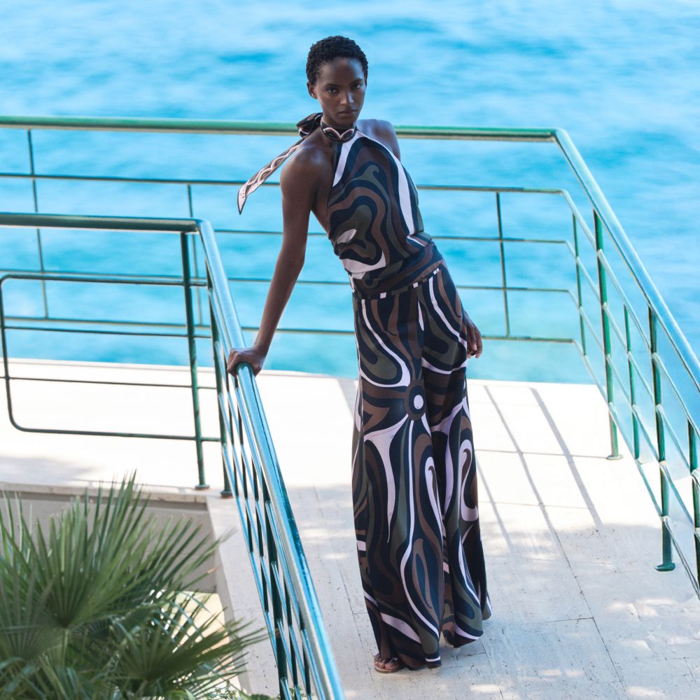 Model wearing a printed Pucci dress beside the water in the Mytheresa campaign