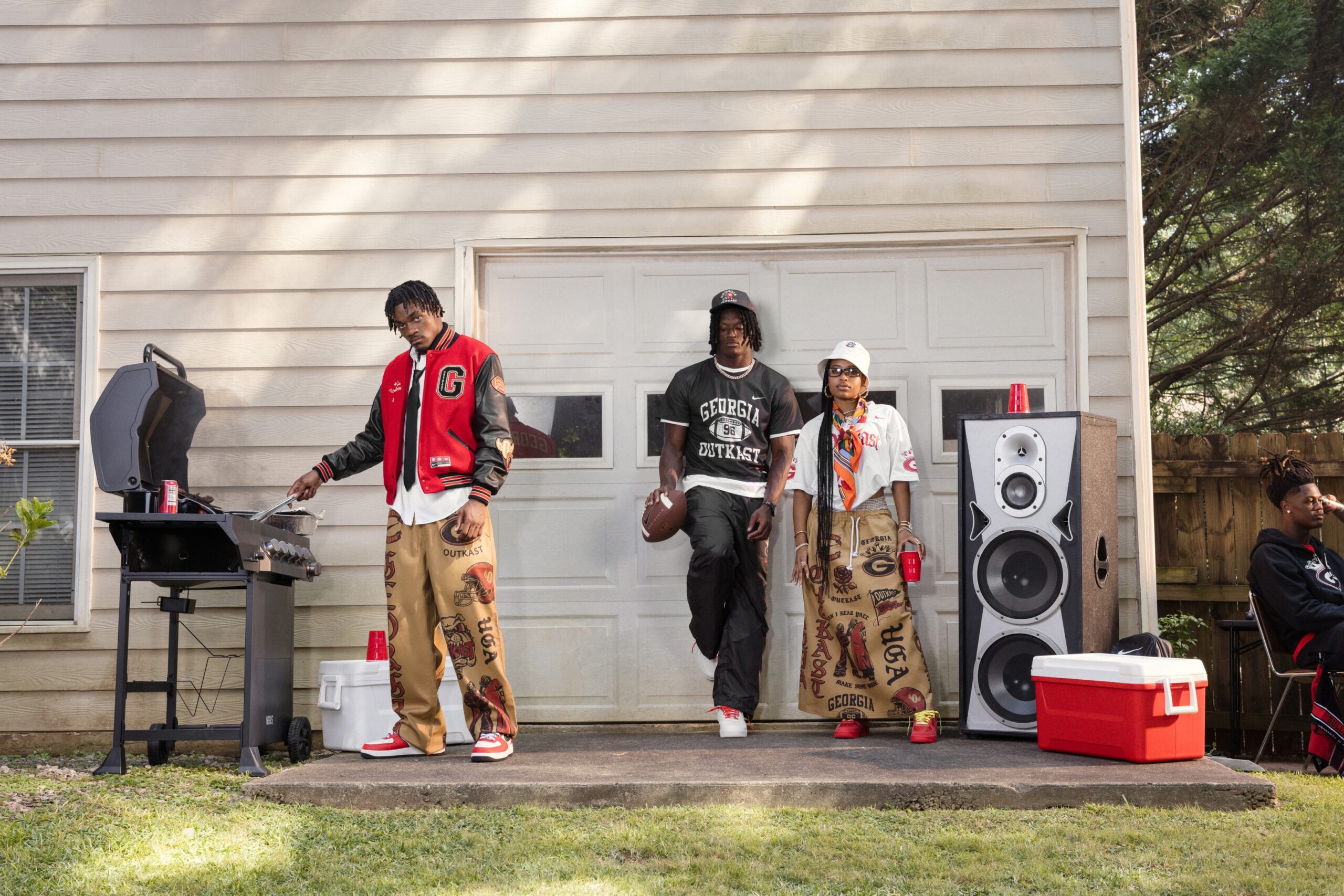 Two Nike NIL athletes in Georgia x Outkast apparel beside a sound system