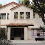 Our Legacy Shanghai villa exterior with pale walls, dark window frames and courtyard trees