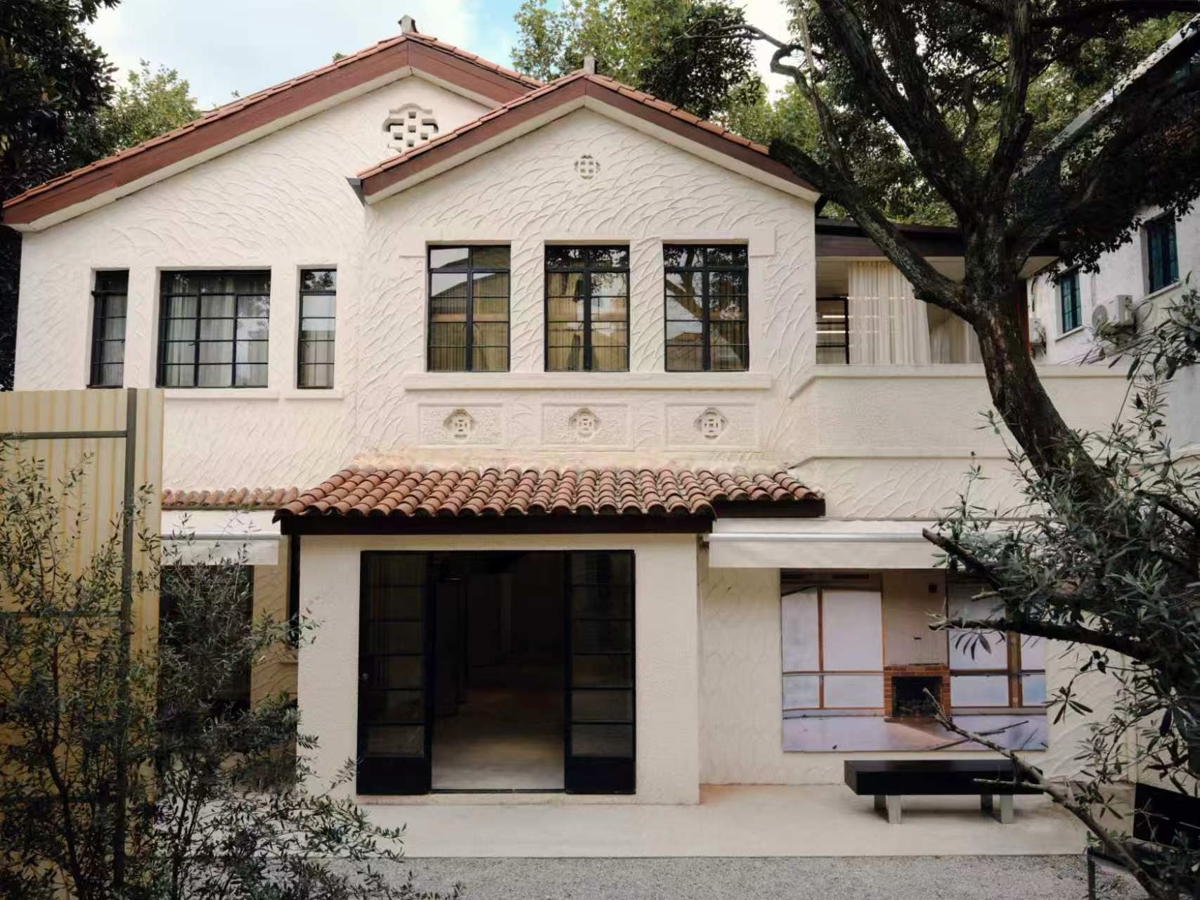 Our Legacy Shanghai villa exterior with pale walls, dark window frames and courtyard trees