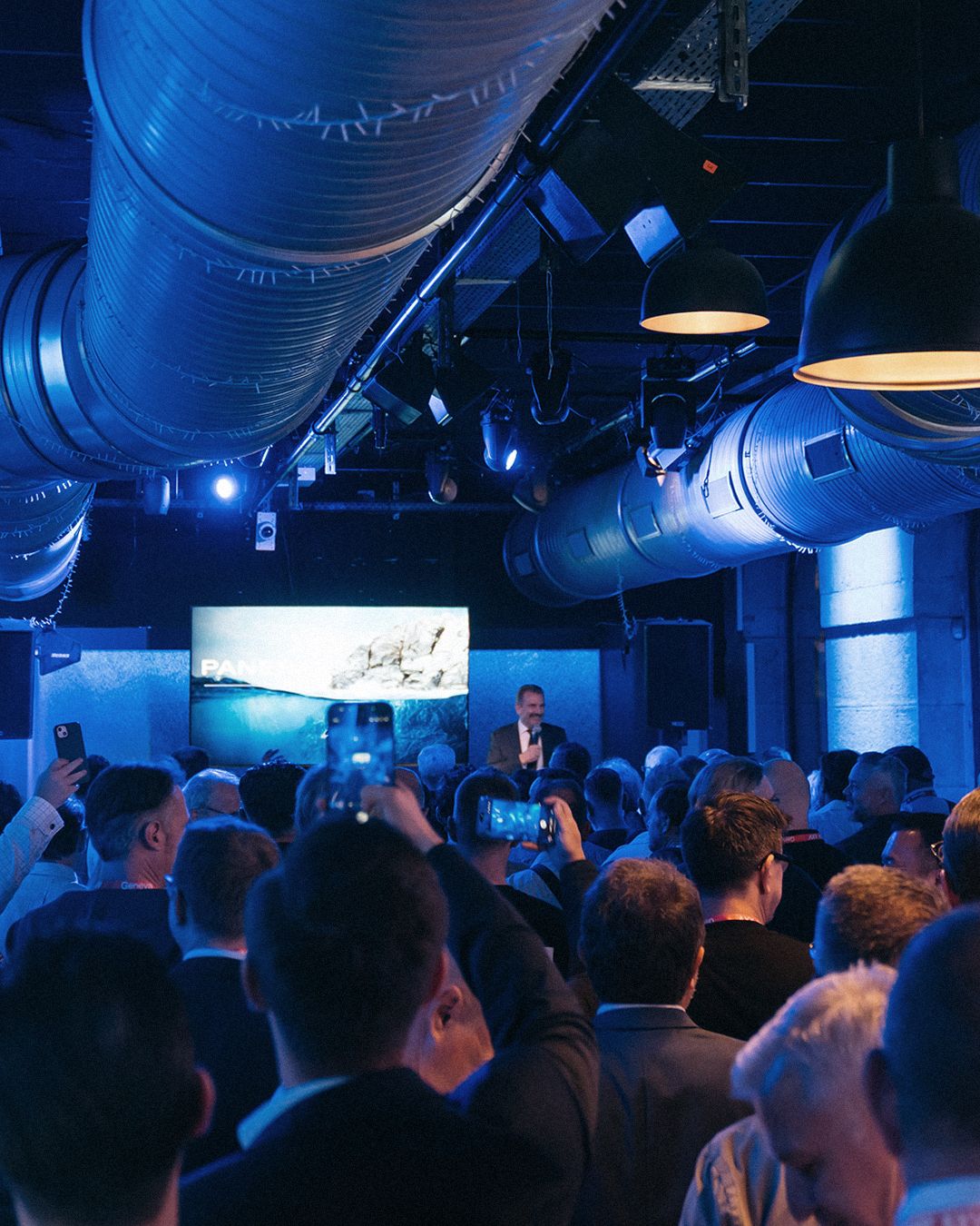 Guests attend a presentation in a blue-lit Panerai event space