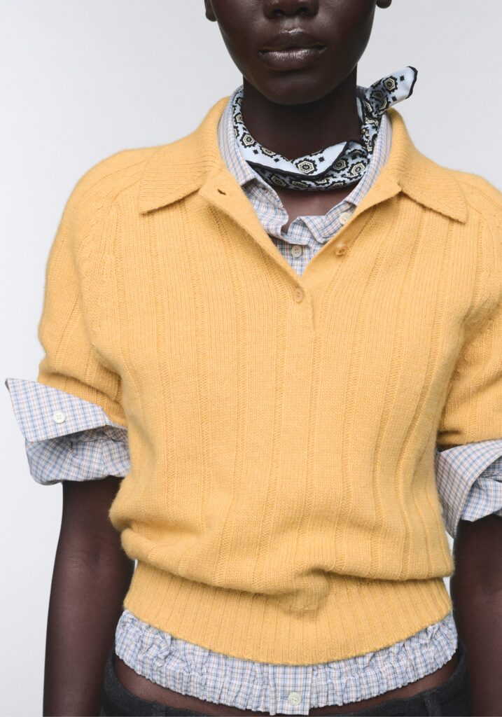 Model in a yellow Prada Re-Cashmere knit polo layered over a checked shirt