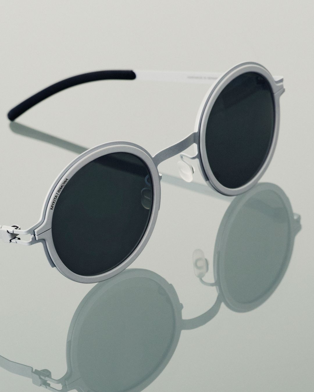 Silver round MYKITA RIMOWA Heritage sunglasses on a reflective surface