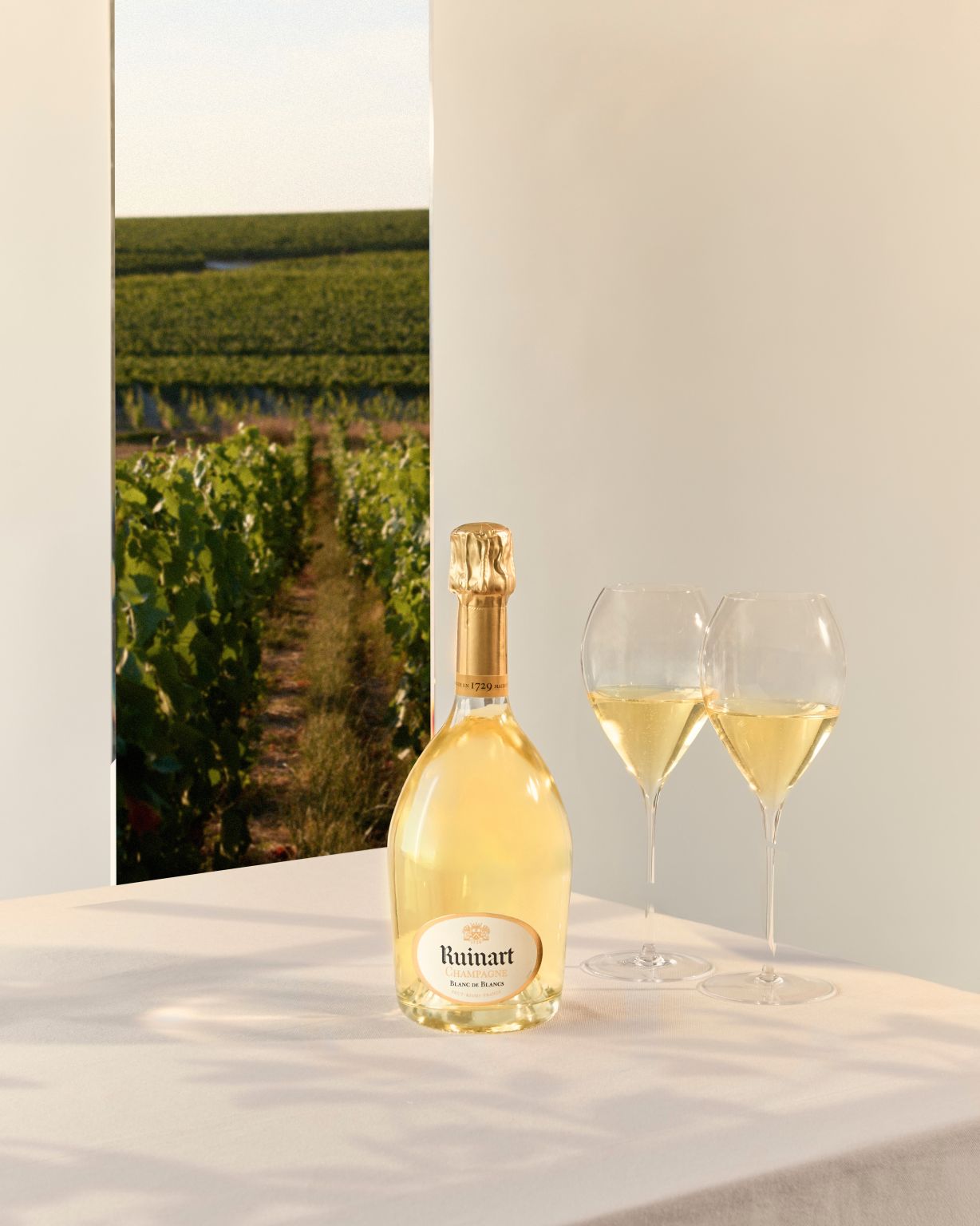 Ruinart champagne bottle and glasses against a pale architectural setting