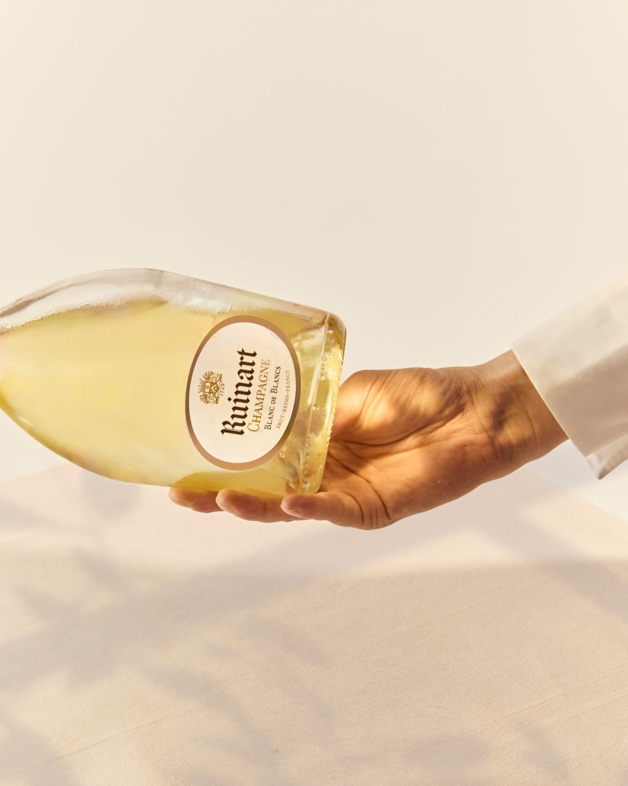 A bottle of Ruinart champagne being poured into a glass