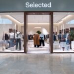 SELECTED storefront with glass doors, clothing displays and a view into the store.