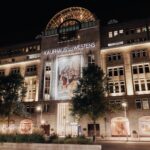 KaDeWe Berlin exterior at night with UGG branding across its facade and windows