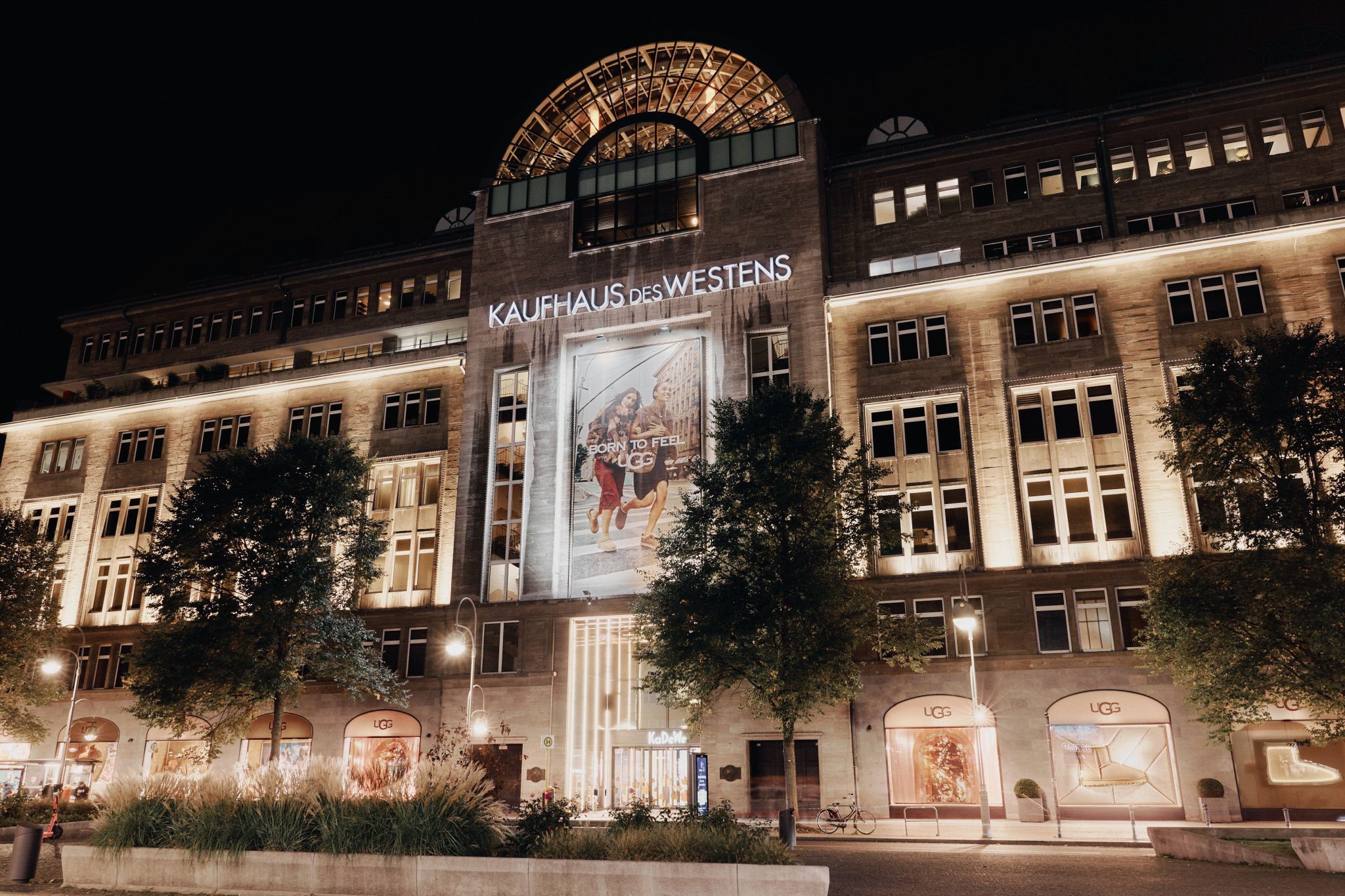 KaDeWe Berlin exterior at night with UGG branding across its facade and windows