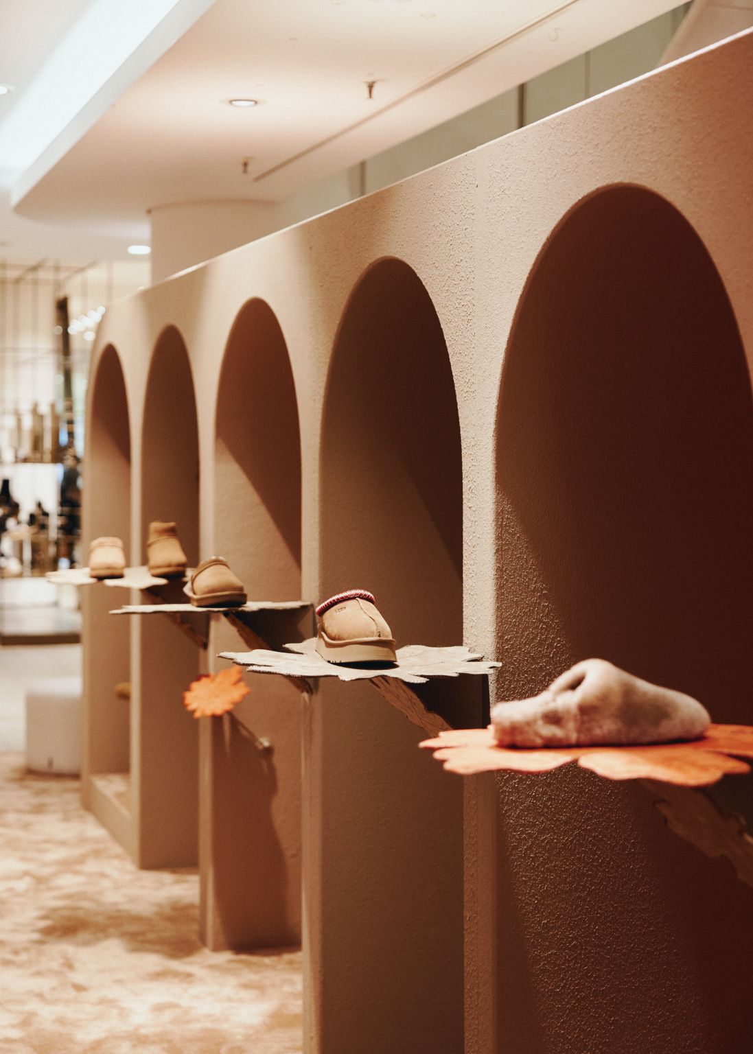 UGG shoes and accessories arranged within arched in-store shelves at KaDeWe