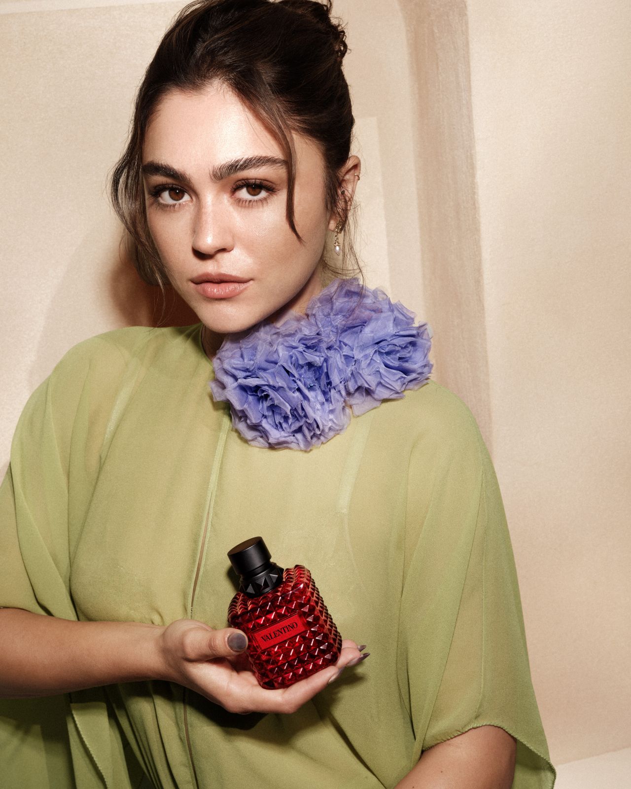 Guest poses with a red Valentino fragrance bottle