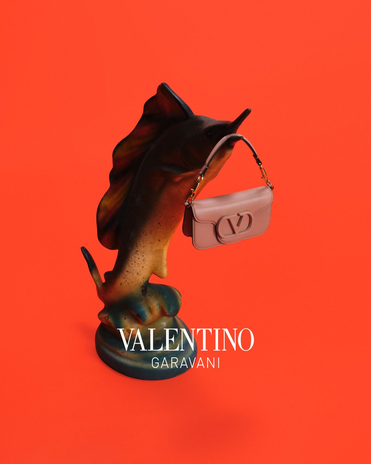 Valentino handbag beside a dark flower against a red background