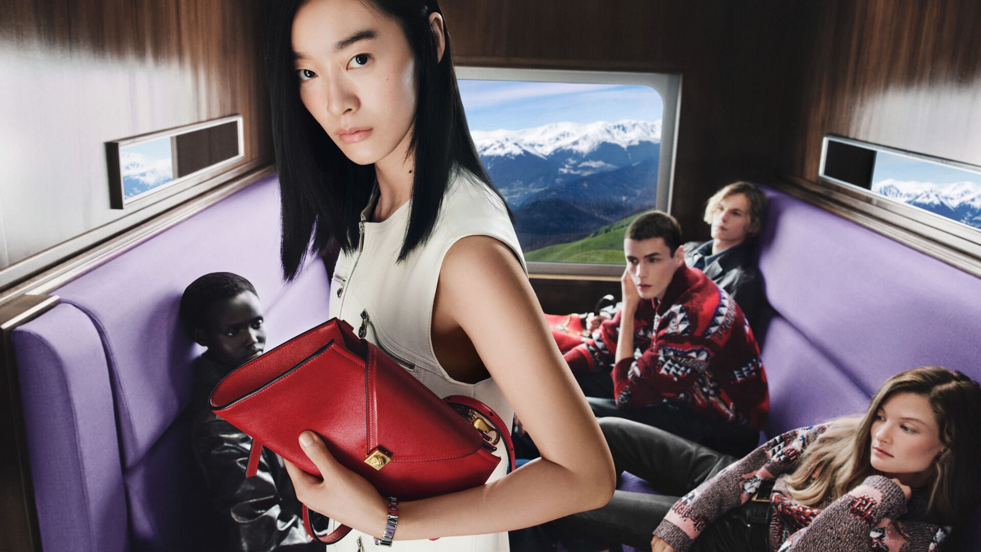 Versace Holiday 2026 cast in a lavender-seated train carriage