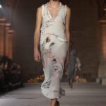Model in a floral Victoria Beckham Spring Summer 2027 dress with beaded edging on the runway