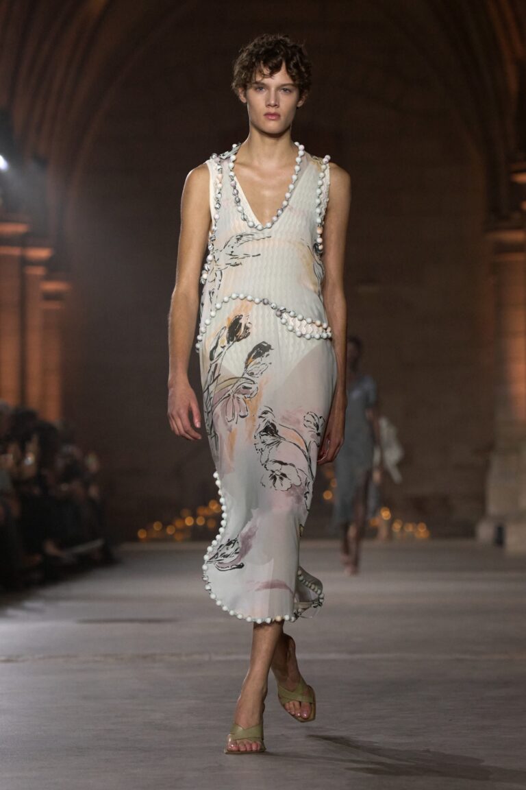 Model in a floral Victoria Beckham Spring Summer 2027 dress with beaded edging on the runway