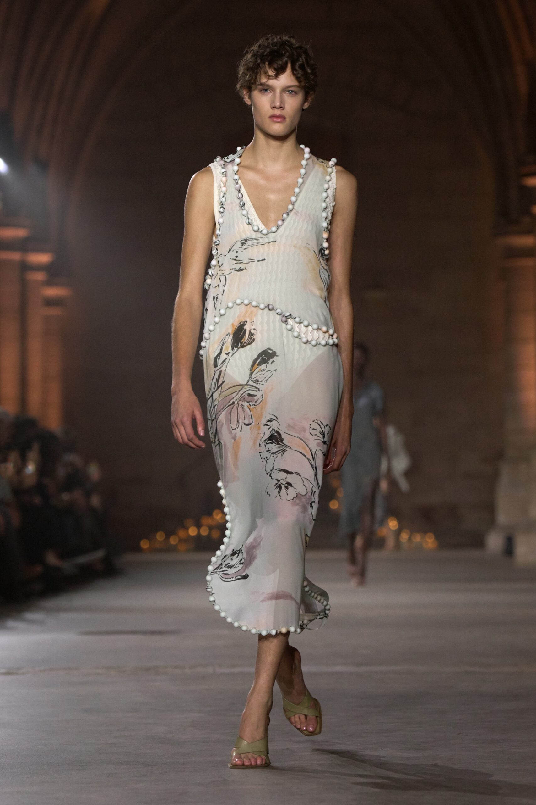 Model in a floral Victoria Beckham Spring Summer 2027 dress with beaded edging on the runway