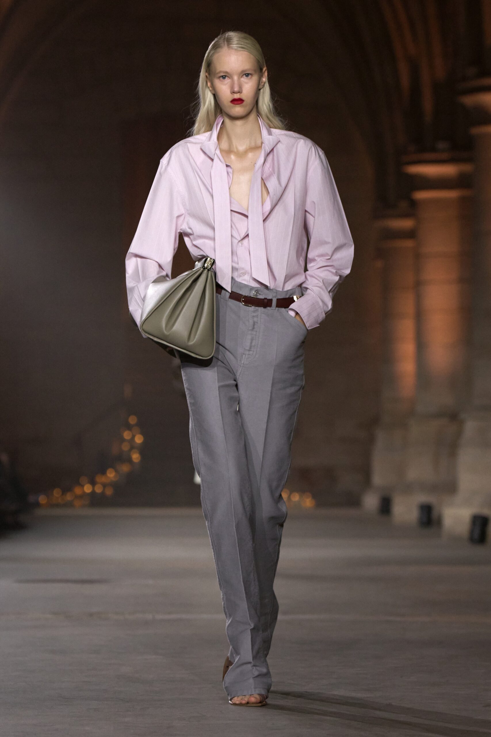 Model in a pink shirt and grey trousers carrying a bag at the Victoria Beckham Spring Summer 2027 show