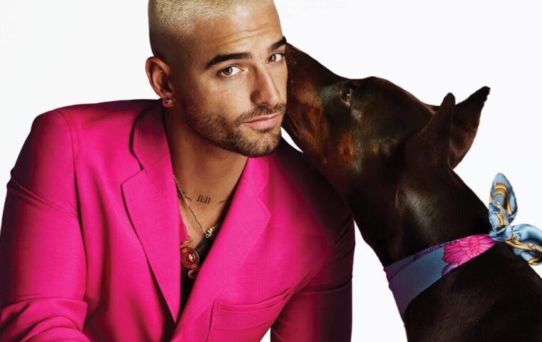 Man in a bright pink suit beside a dog wearing a patterned scarf