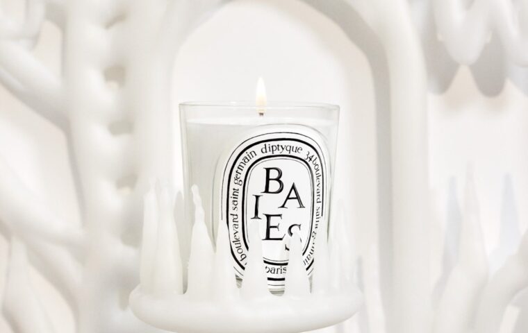Lit Diptyque Baies candle against a white sculptural backdrop